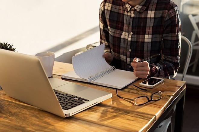 image of UC student in flannel shirt studying with notebook and laptop